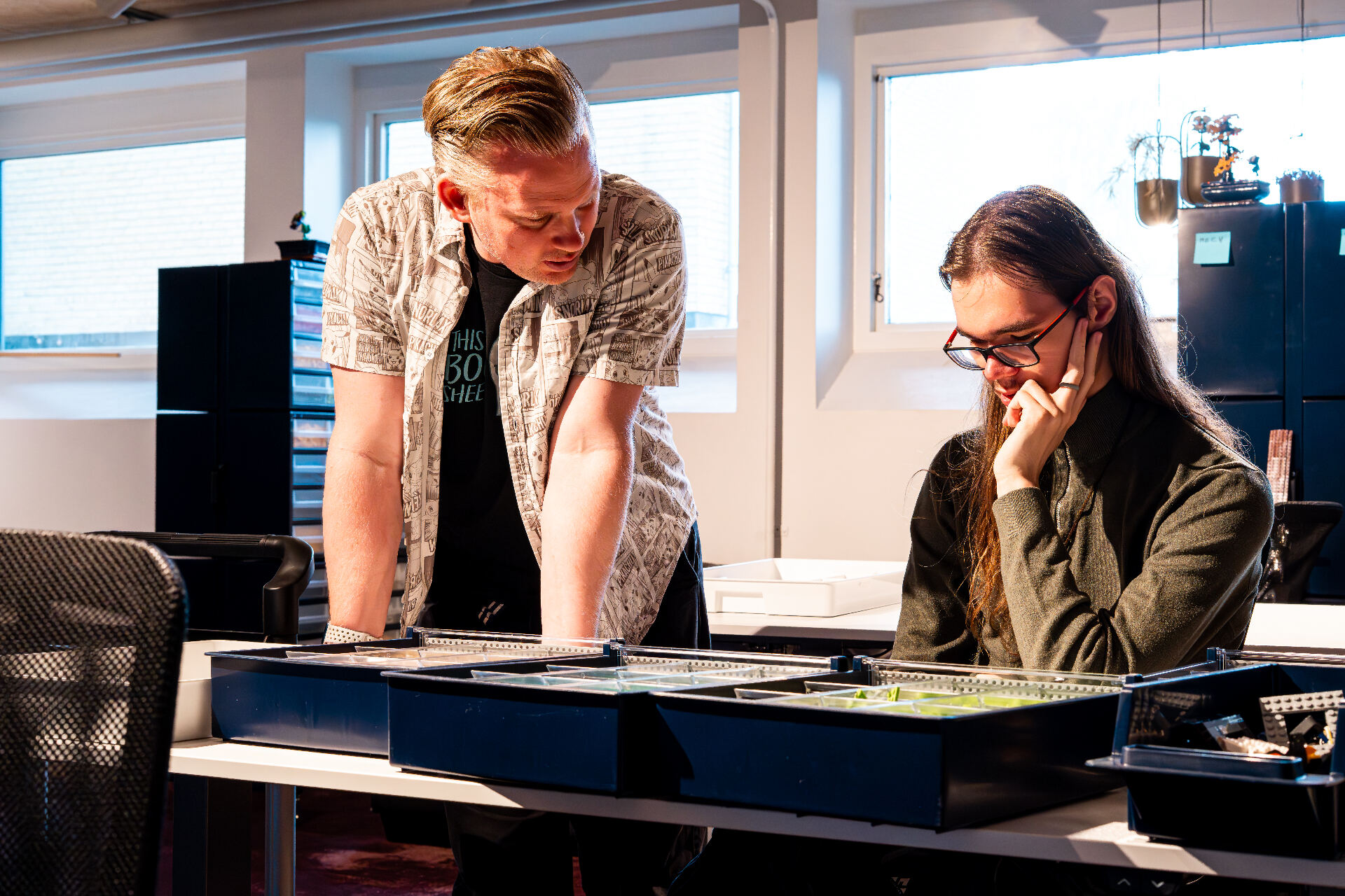 To personer ved et bord med LEGO-klodser i Brick Academy